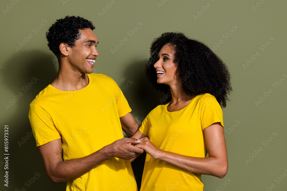 Portrait of two nice people hold arms laugh wear t-shirt isolated on khaki color background Portrait of two nice people hold arms laugh wear t-shirt isolated on khaki color background
