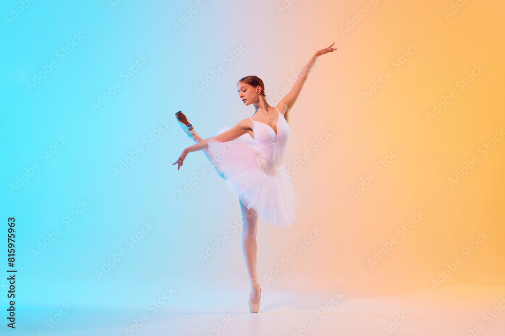 Young ballerina in elegant attire, tutu and pointe, performing in neon light against blue-orange gradient background. Graceful. Concept of art, movement, classical and modern fusion, beauty, fashion. Young ballerina in elegant attire, tutu and pointe, performing in neon light against blue-orange gradient background. Graceful. Concept of art, movement, classical and modern fusion, beauty, fashion.