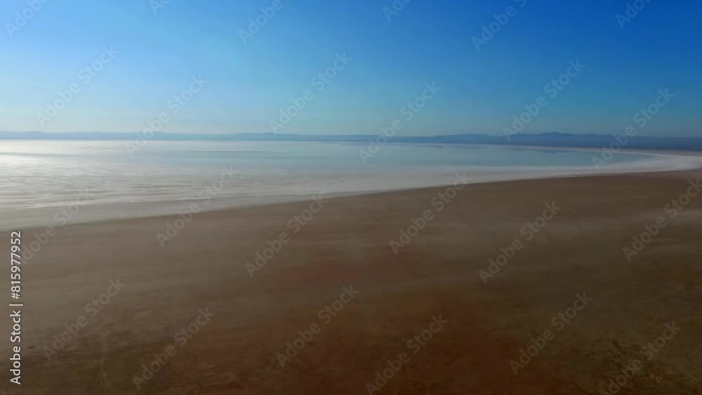 Aerial view of the tranquil salt lake in the vast expanse of crystal clear waters surrounded by sand.