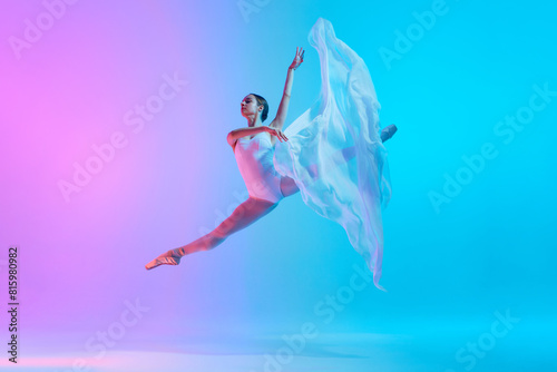 Ballet dancer performs jumping split in motion with flowing white cloth in neon light against vivid gradient background. Concept of art, movement, classical and modern fusion, beauty and fashion. Ad