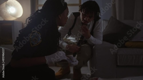 A policewoman and a man investigate a crime scene at a new york home, evaluating evidence indoors. photo