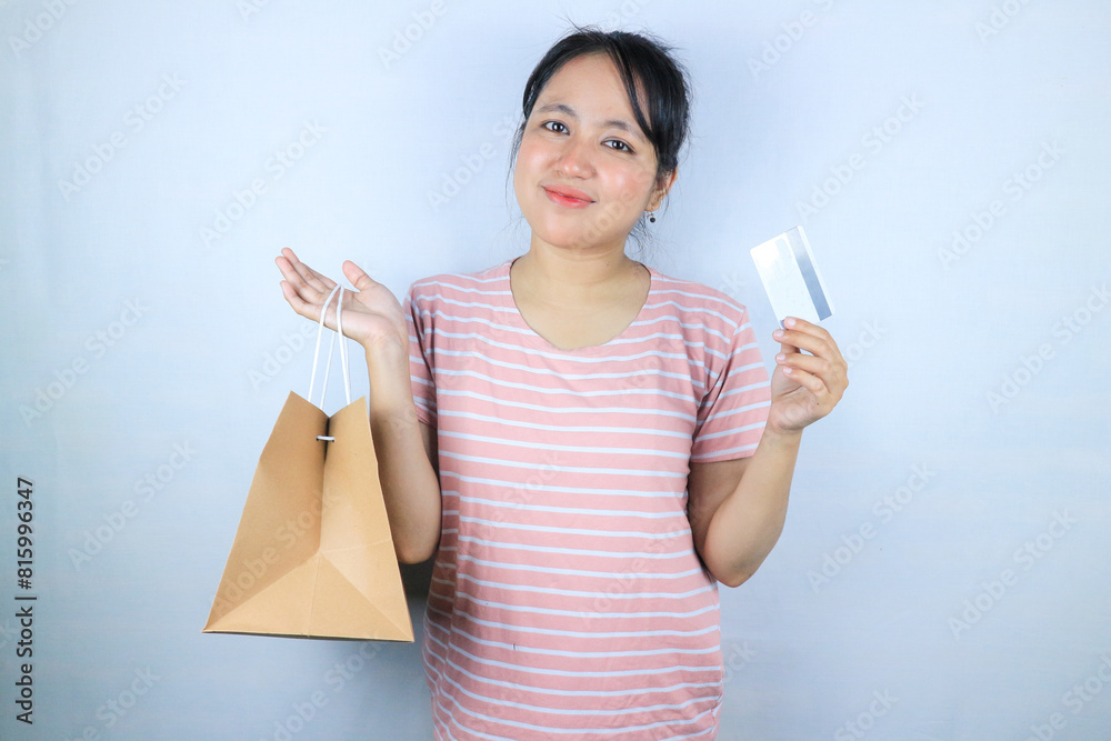 Young beautiful Asian woman holding paper shopping bag and showing credit card. Fashion mall concept Young beautiful Asian woman holding paper shopping bag and showing credit card. Fashion mall concept