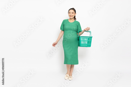 Asian pregnant woman smile and holding green grocery basket isolated on white background, Shopping and Supermarket concept, Full body composition