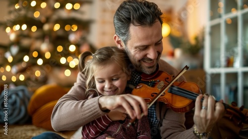 Father teaching young daughter to play violin at home with Christmas tree in the background  sharing joyful moment together.