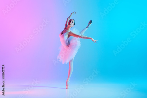 Portrait of young, flexible ballerina dancing, standing on tiptoe in action in neon light against vivid gradient background. Concept of art, movement, classical and modern fusion, beauty and fashion.