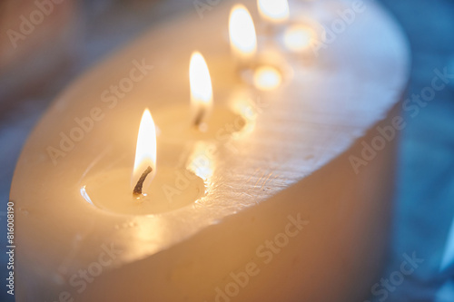 Natural wax candle with several wicks lit inside the home to create a cozy atmosphere. Decorative elements in the home.