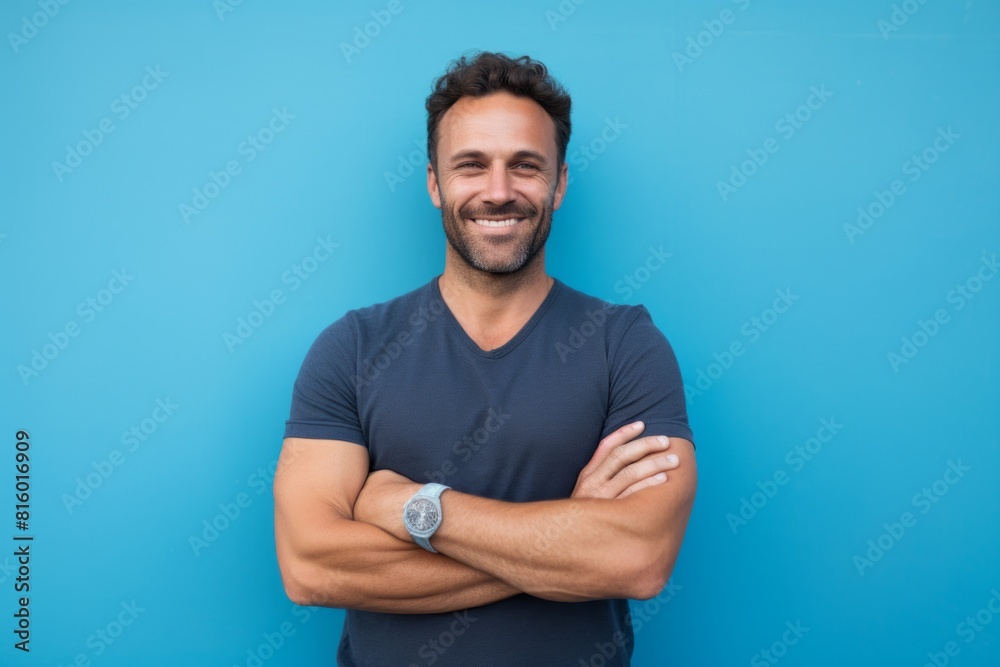 Portrait of a cheerful man in his 30s with arms crossed isolated on soft blue background