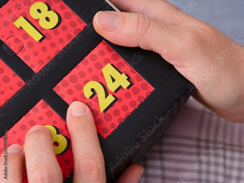 A woman hands ready to open the door with number 24 on the advent calendar.
