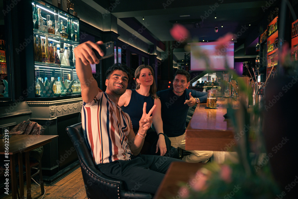 Group of friends taking a selfie at a bar in the evening