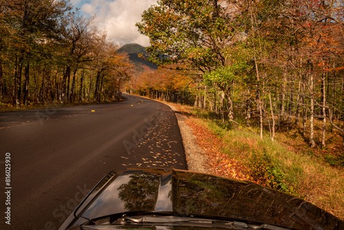   A car on a deserted road in the middle of a forest in the autumn mountains. Traveling around the USA