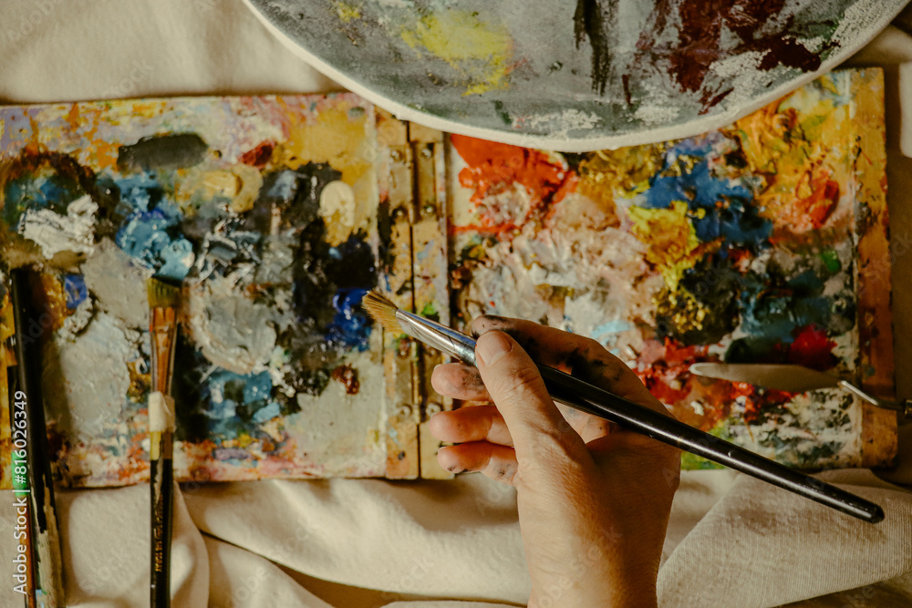 Woman's hand carrying paint brush on canvas