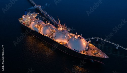 Aerial of Liquified Natural Gas LNG carrier moored to a small gas terminal at night. Fuel crisis. Sanctions.