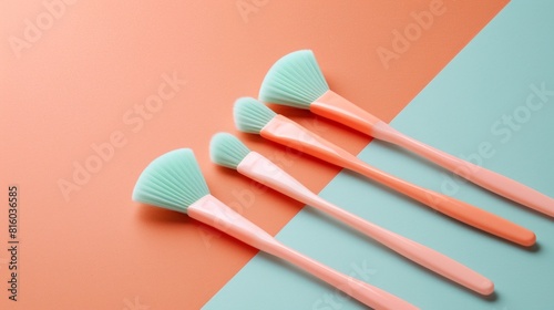 A set of four silicone brushes arranged on a colorful background. The brushes have mint green bristles and peach-colored handles, showcasing a modern and stylish design