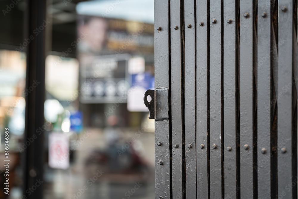 Classic style sliding metal fence gate, it using for cover the glass wall inside. Building place object photo, close-up and selective focus. Classic style sliding metal fence gate, it using for cover the glass wall inside. Building place object photo, close-up and selective focus.