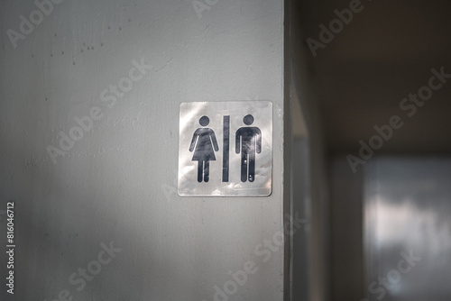 A toilet gender with men and women icon in gray scale banner which is attached on building wall. Sign and symbol object photo. 