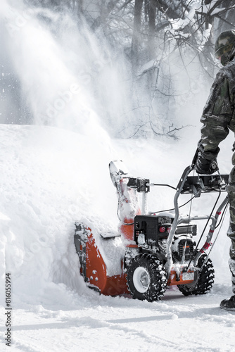 The self-propelled snow-plough blower. The man in warm clothes gloves instead of the big shovel has chosen a self-propelled engine snowplow outdoors