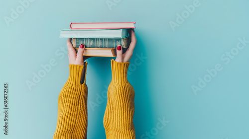 Mãos femininas segurando uma pilha de livros sobre fundo azul claro. Educação, autoaprendizagem, troca de livros, hobby, tempo de relaxamento photo