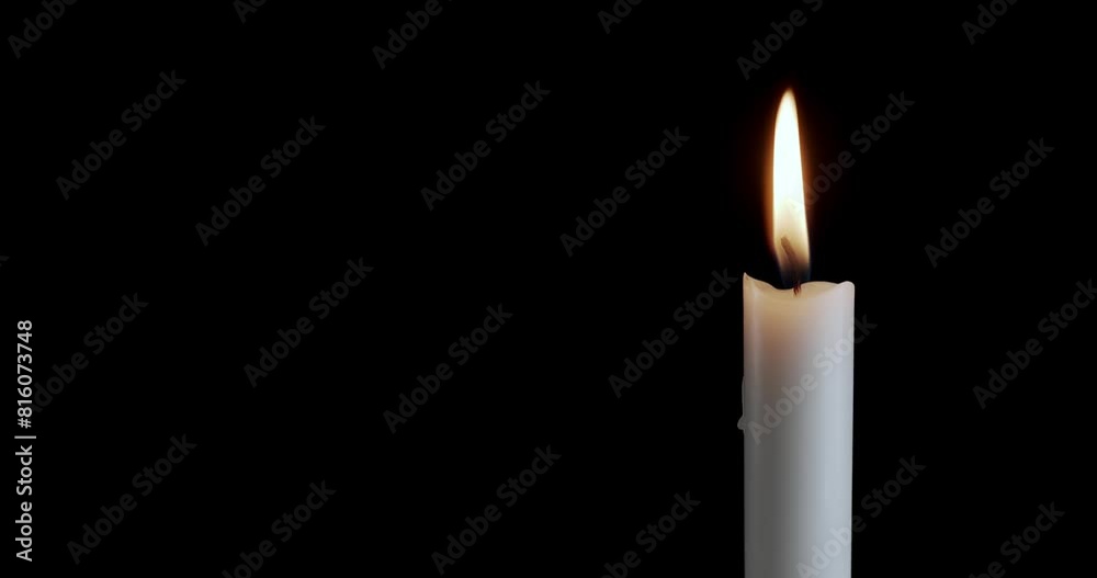 A single white candle burning. Isolated candle slow motion burning with dark background. White paraffin candle with yellow shades burns on a black background. Slow motion.