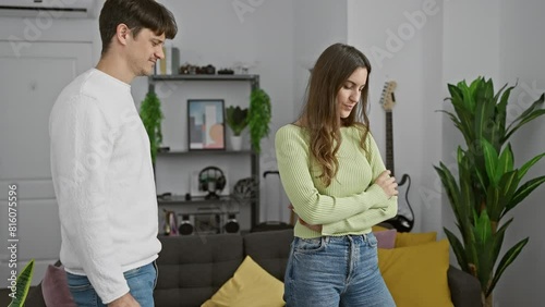 A man and woman in a modern living room engage in a moment of silent disagreement. photo