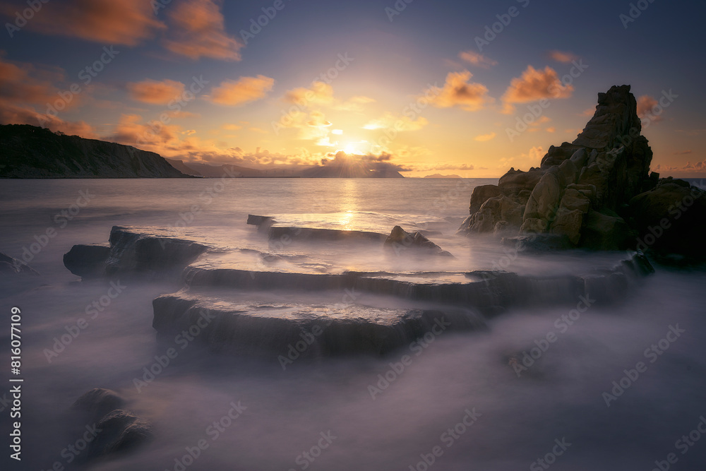 Sunset on Azkorri or Gorrondatxe beach, in Getxo, Bizkaia, with the waves passing over the rocks
