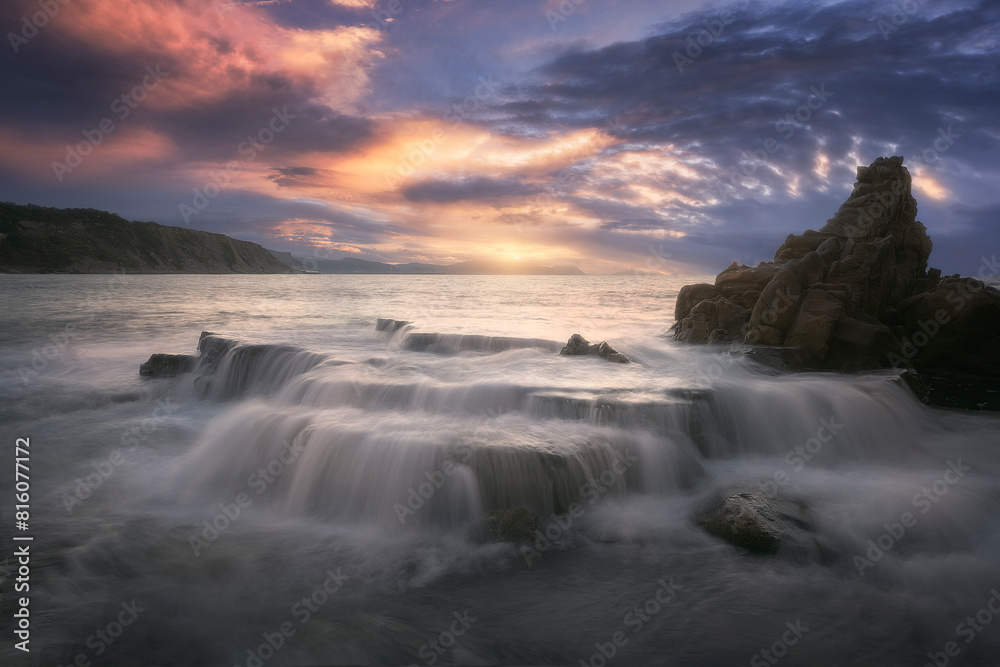 Fototapeta premium Sunset on Azkorri or Gorrondatxe beach, in Getxo, Bizkaia, with the waves passing over the rocks