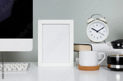 Empty picture frame on table in workspace with computerand coffee cup