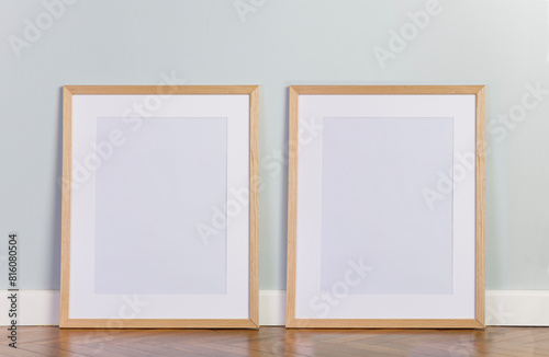 Blank picture frame templates on floor. Mint color wall and stylish parquet floor