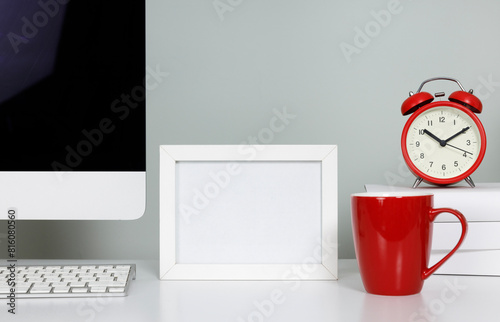 Empty picture frame on table in workspace with computerand coffee cup