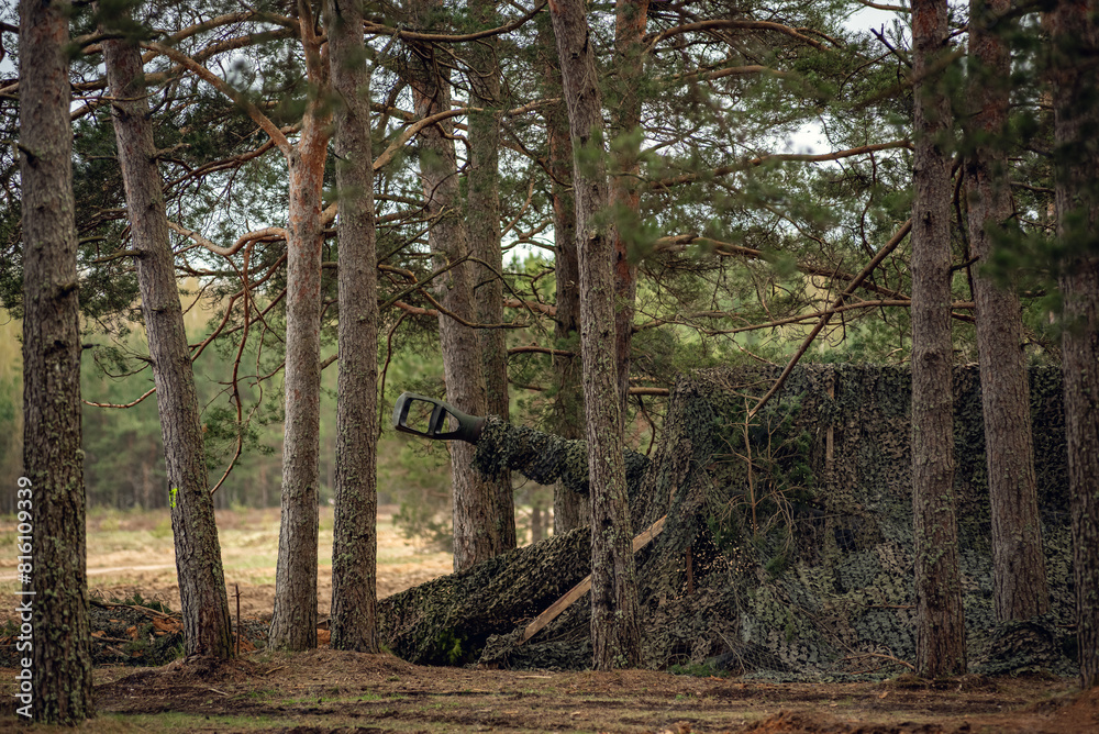 Obraz premium hidden self propelled howitzer with the barrel poking out of the shelter
