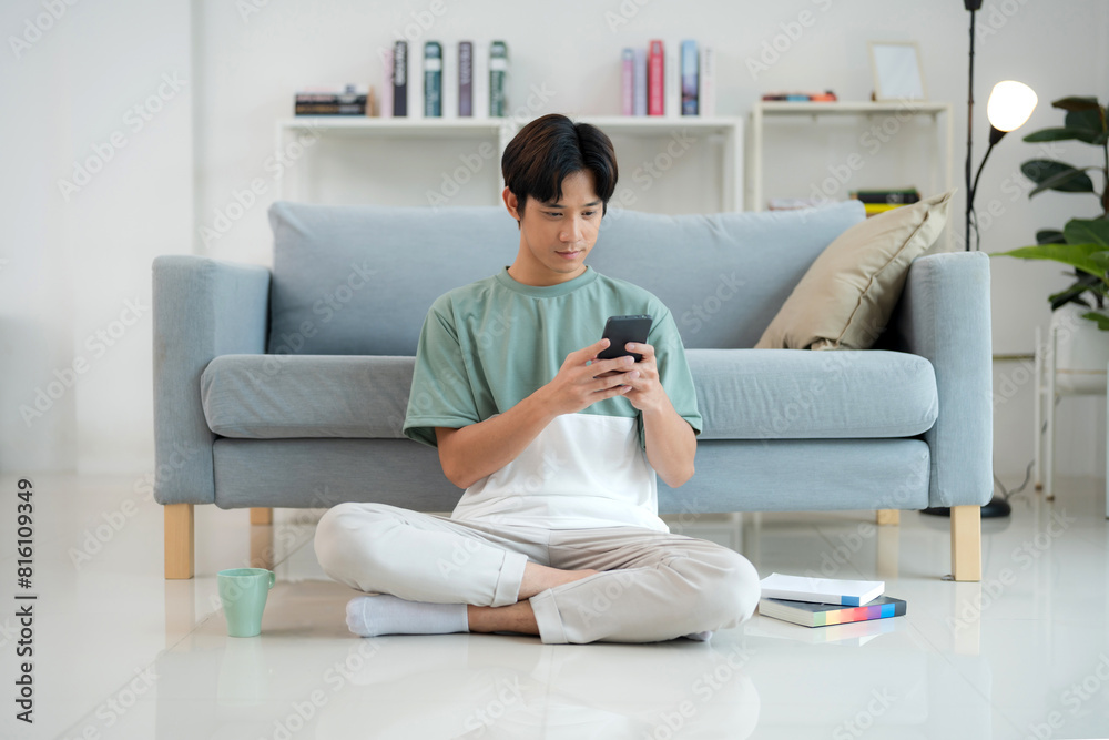 Young man enjoying smartphone in a modern living room Young man enjoying smartphone in a modern living room