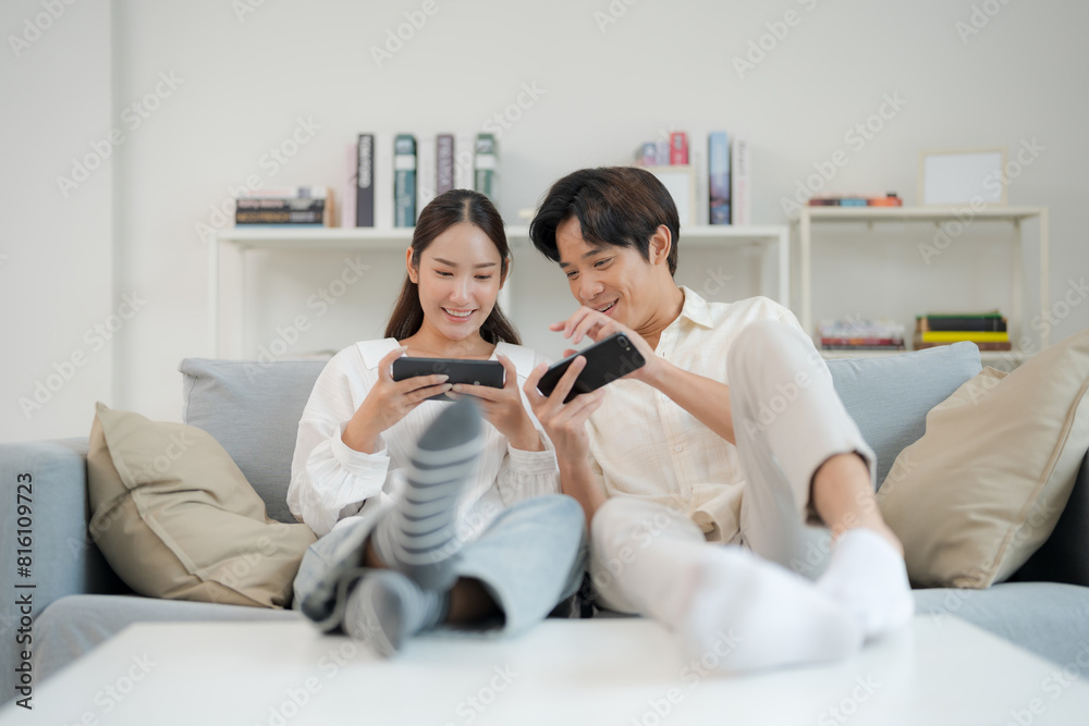 Excited young couple playing smartphone games on couch