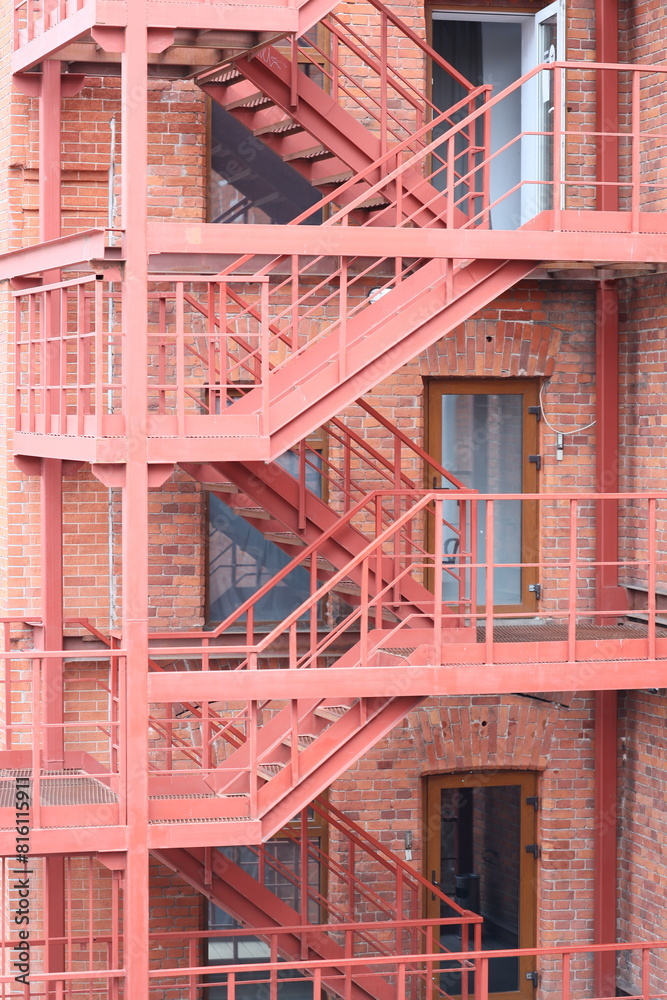 A red fire escape staircase next to a brick building. Suitable for urban architecture concepts