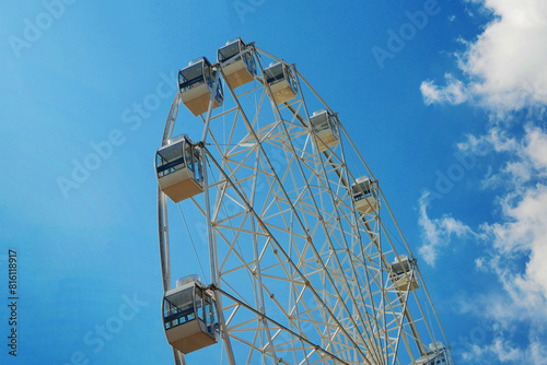 Ferris wheel on blue sky background. Blue sky with white clouds.