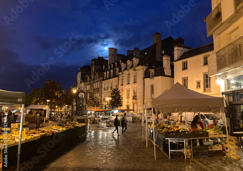 Vendors prepare their flower and food stalls in early morning under a full moon for the Saturday Lices Market in Rennes, Brittany, France, one of the largest outdoor markets in Europe.