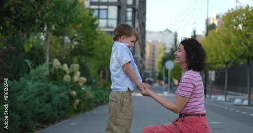 Adorable caucasian mother and son kid smiling laughing and hugging having fun at city urban background. Motherhood concept 8 years old boy with mother in bright clothes enjoying summer day