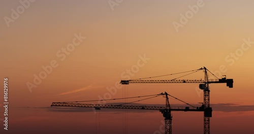 Time lapse of working cranes on the beautiful sunset sky background. Close-up. Aerial view