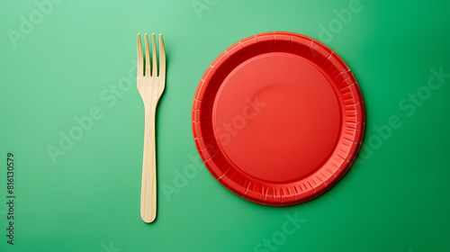 Wooden fork and empty round red disposable plate made from recycled materials on a green background top view Concept of the absence of nonrecyclable garbage rejection of plastic : Generative AI photo