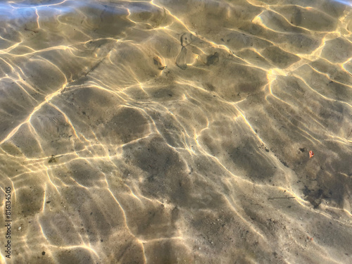 Surface of the water. Sun glare. Sandy bottom. 