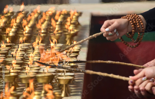 Candles in a temple are lit by hands