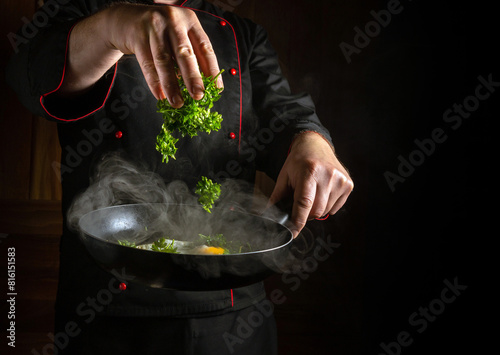 Cooking scrambled eggs with parsley in a frying pan. The cook hand throws fresh parsley into the scrambled eggs.