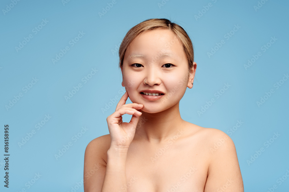 Pretty Asian girl holding hand on the cheek looking at camera, isolated. Spa concept Pretty Asian girl holding hand on the cheek looking at camera, isolated. Spa concept
