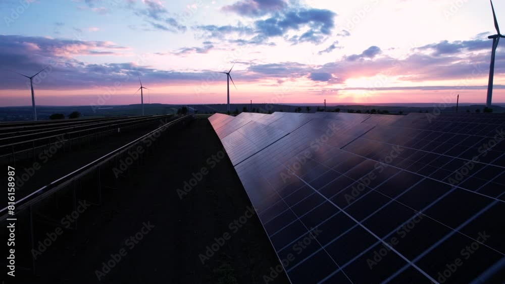 Photovoltaic power station and wind turbines at sunset.Windmill turbines generating green energy electric.Green energy reduce carbon emissions and makes earth cleaner and more ecological.