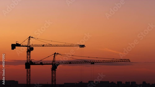 Time lapse of working cranes on the beautiful sunset sky background. Close-up. Aerial view