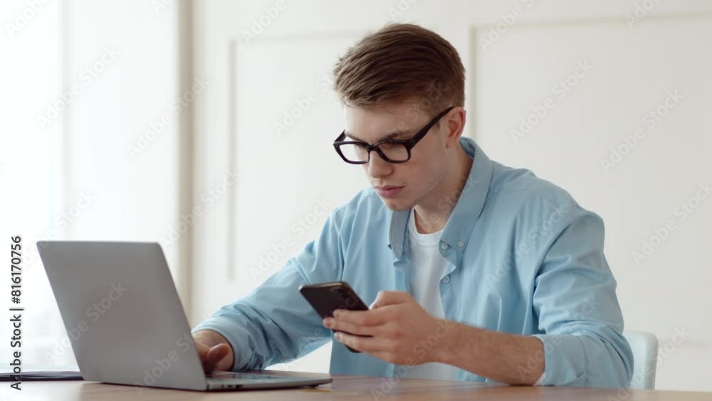 Mobile banking and two factor authentication. Young man entering credit card data and security password from cell phone on laptop at home workplace