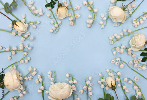 White flowers Lily of the valley ( Convallaria majalis, May bells, may lily ), white roses on a blue paper background with space for text. Top view, flat lay © Anastasiia Malinich