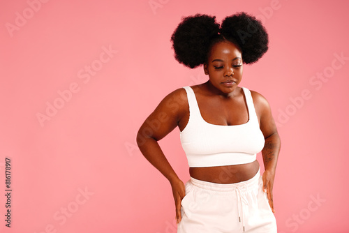 Beautiful woman with afro hairstyle posing on pink pastel studio background.
