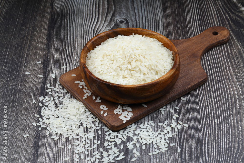 Raw white rice on wooden background. Long uncooked rice in wooden plate. Natural organic food. Traditional Asian cereal culture. Raw white rice on wooden background. Long uncooked rice in wooden plate. Natural organic food. Traditional Asian cereal culture.