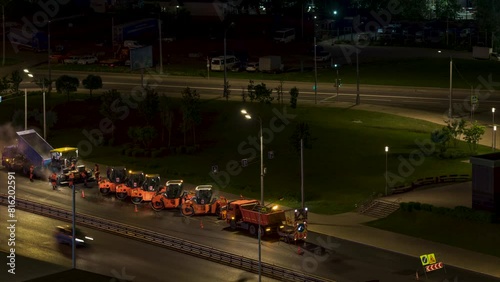 Time lapse. of working asphalt rollers on the busy highway at night. High angle view. Close-up