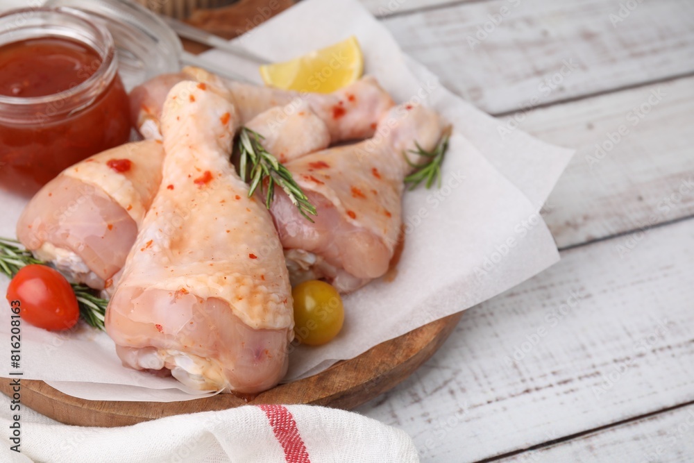 Marinade, raw chicken drumsticks, rosemary and tomatoes on white wooden table. Space for text Marinade, raw chicken drumsticks, rosemary and tomatoes on white wooden table. Space for text