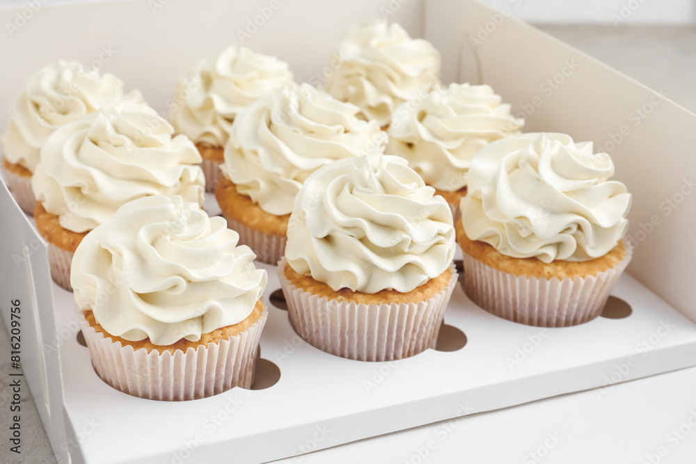 Tasty cupcakes with vanilla cream in box, closeup Tasty cupcakes with vanilla cream in box, closeup